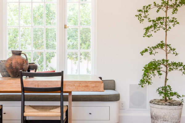 Mediterranean-style dining nook with a custom built-in window bench, tall divided-light windows, terracotta floors, and a rustic wood dining table in a Tampa, Florida home remodeled by Driftwood Studio Inc.